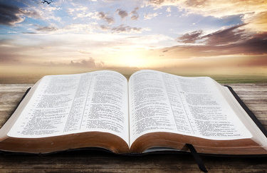 "Open Bible with beautiful sunset"